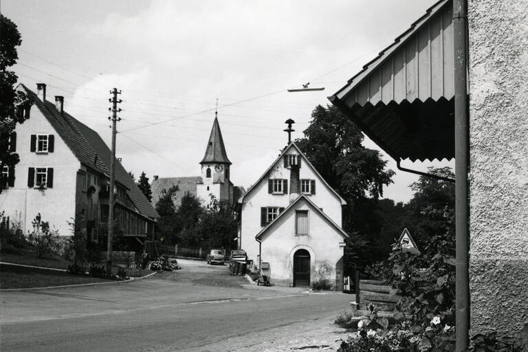 Historische Schwarzweißfotografie einer Straße in Lichtenstein-Holzelfingen. Im Hintergrund ist die Blasiuskirche zu sehen.