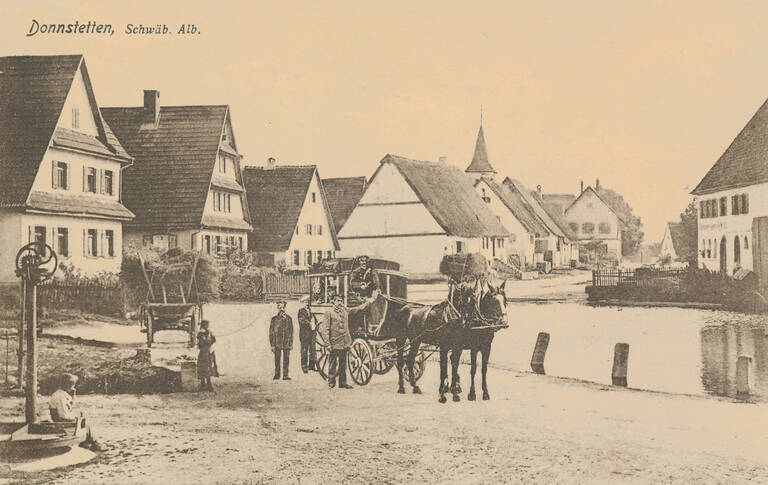 Historische Ansichtskarte von Römerstein-Donnstetten in Schwarz-weiß. Abgebildet ist eine Dorfstraße. Oben die Aufschrift "Donnstetten, Schwäb. Alb."