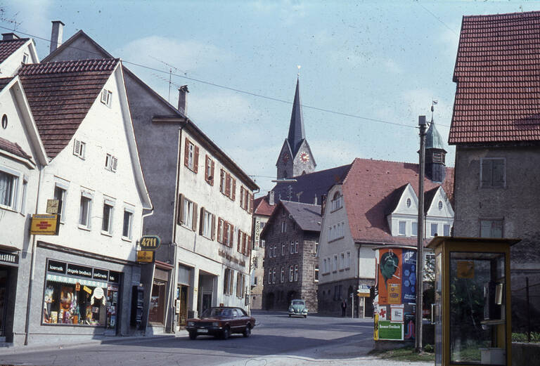 Historische Fotografie einer Straße in Reutlingen-Gönningen. Im Hintergrund ist die Evangelische Kirche Peter und Paul Gönningen zu sehen.